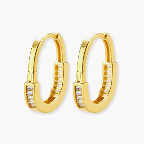 Close-up of gold-plated sterling silver huggie hoop earrings featuring rectangular cubic zirconia stones on neutral background.