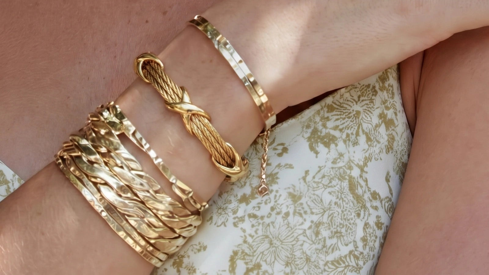 Twisted cable bracelet in gold featuring polished X-shaped knots, elegantly worn alongside other bracelets.