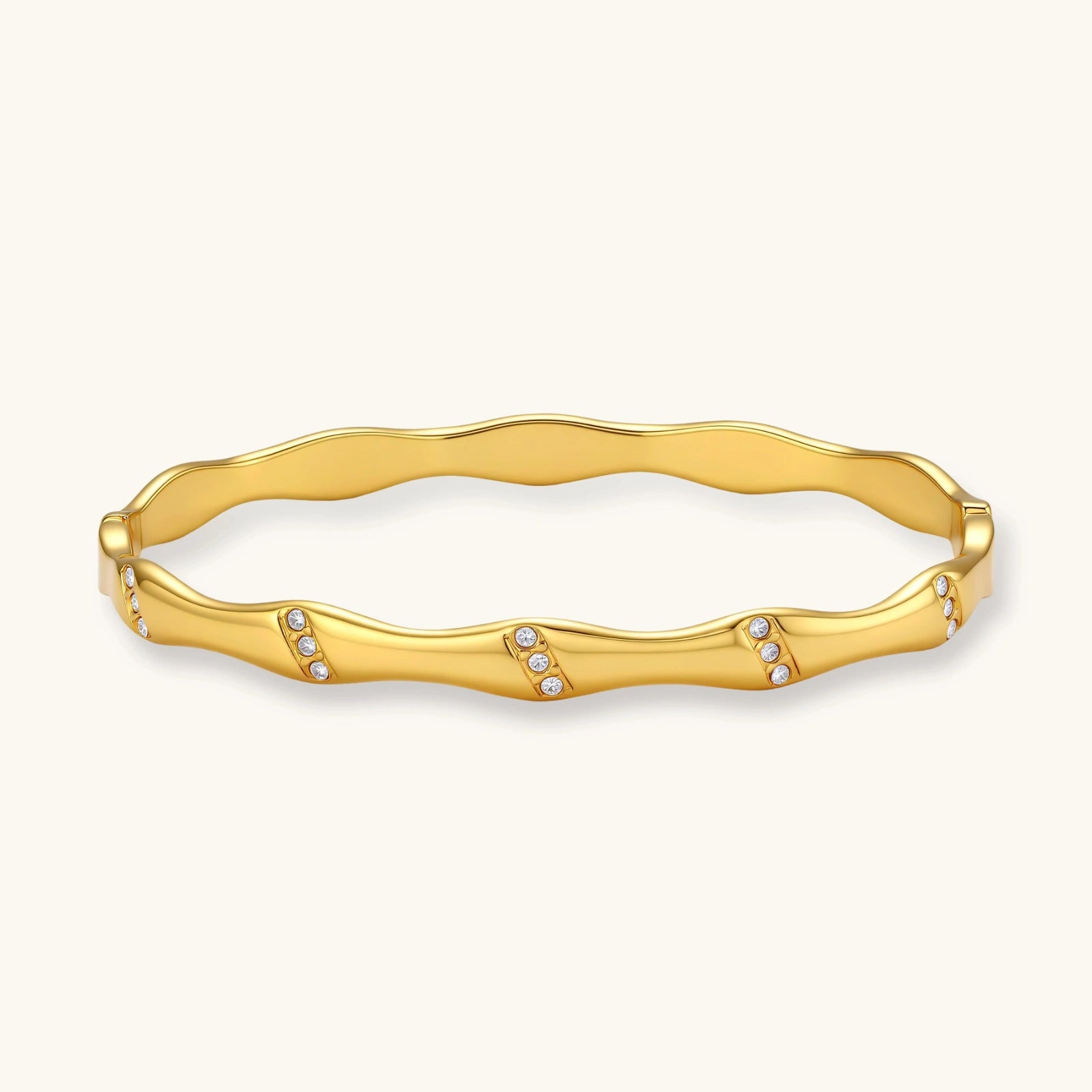 Gold-toned wavy bangle featuring delicate clusters of stones, designed for effortless elegance.