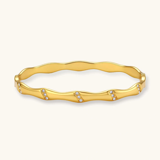 Gold-toned wavy bangle featuring delicate clusters of stones, designed for effortless elegance.