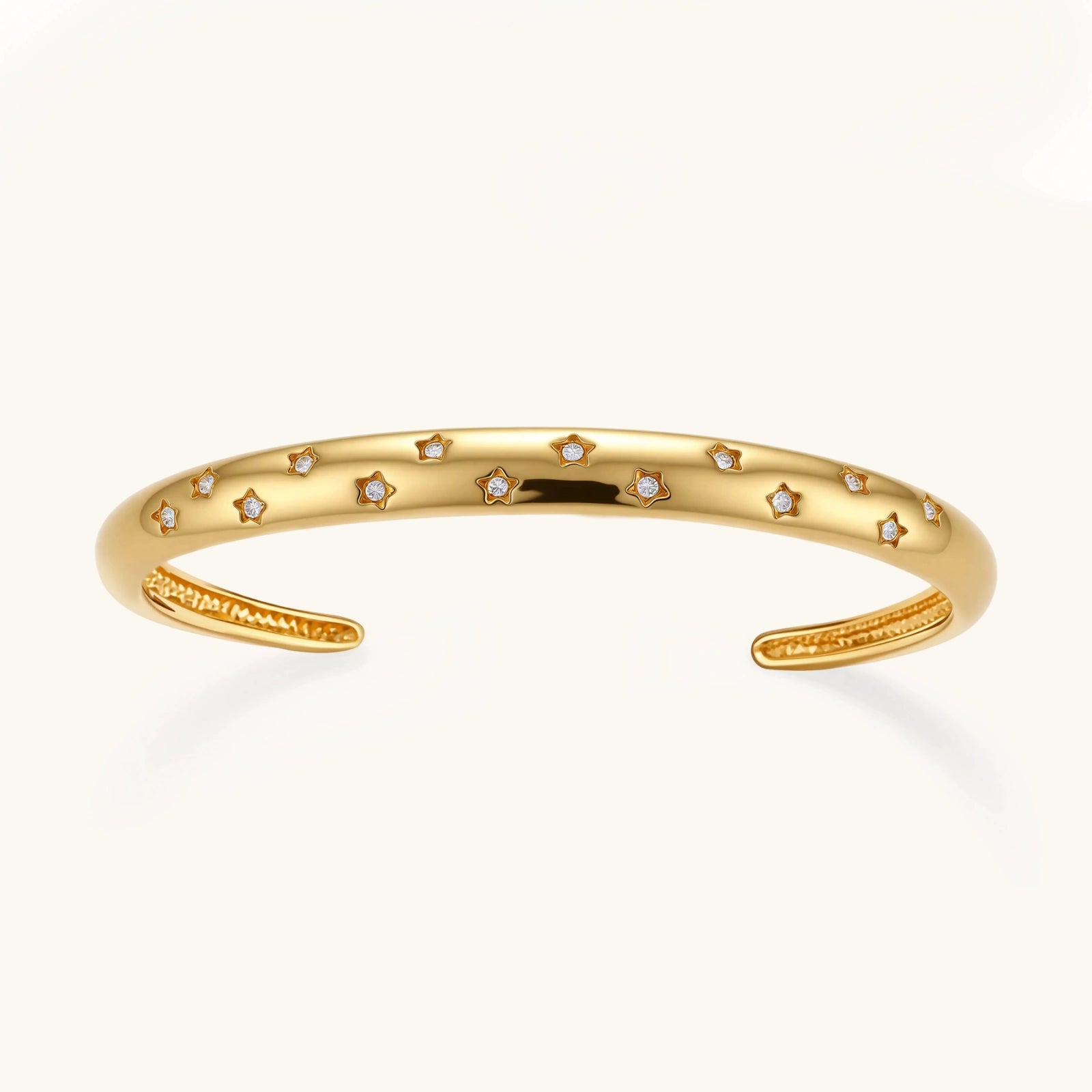 Polished gold cuff bracelet featuring evenly spaced star motifs in an open design, embodying celestial elegance.
