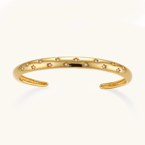 Polished gold cuff bracelet featuring evenly spaced star motifs in an open design, embodying celestial elegance.