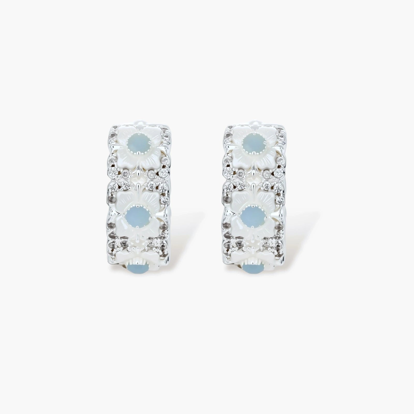 Silver-plated hoop earrings featuring delicate daisy flowers with powder blue centers and crystal accents on white background.