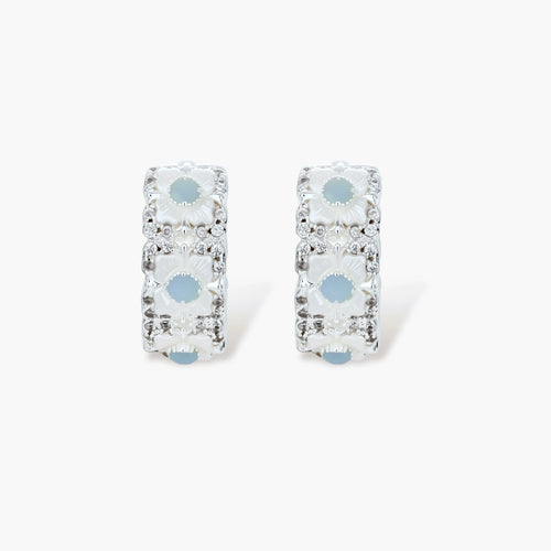Silver-plated hoop earrings featuring delicate daisy flowers with powder blue centers and crystal accents on white background.