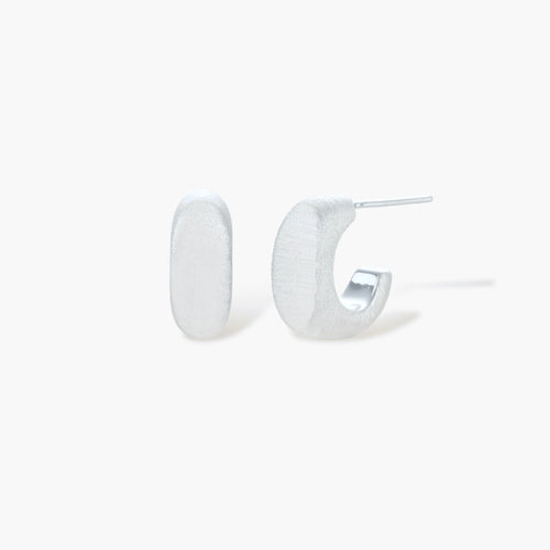 Pair of small silver-plated huggie hoop earrings with clean minimal design on neutral background.