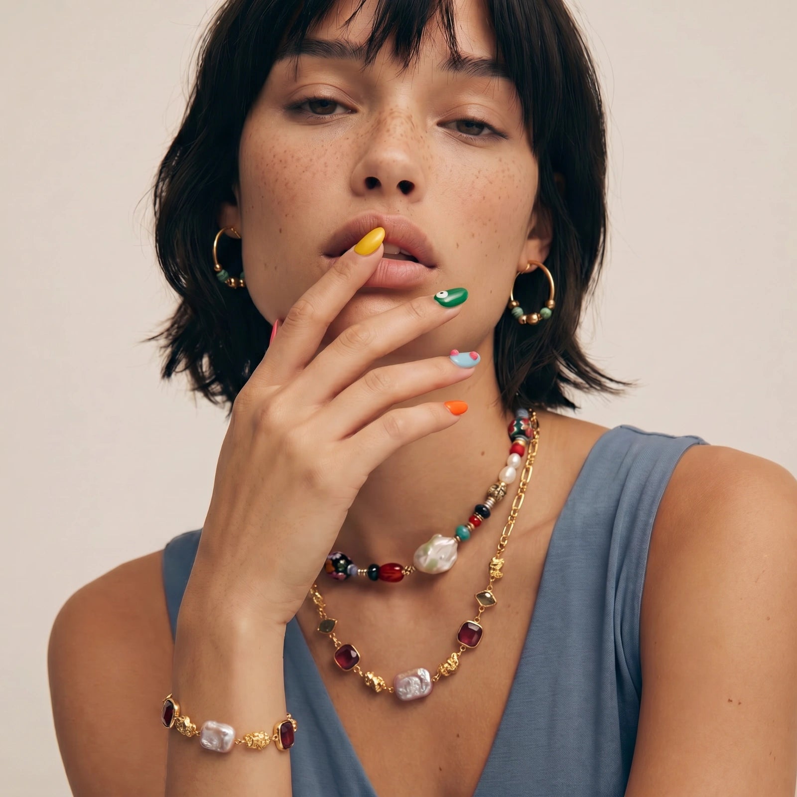 Bracelet showcasing deep red stones, pink freshwater pearls, and hammered gold nuggets, elegantly worn on a wrist.