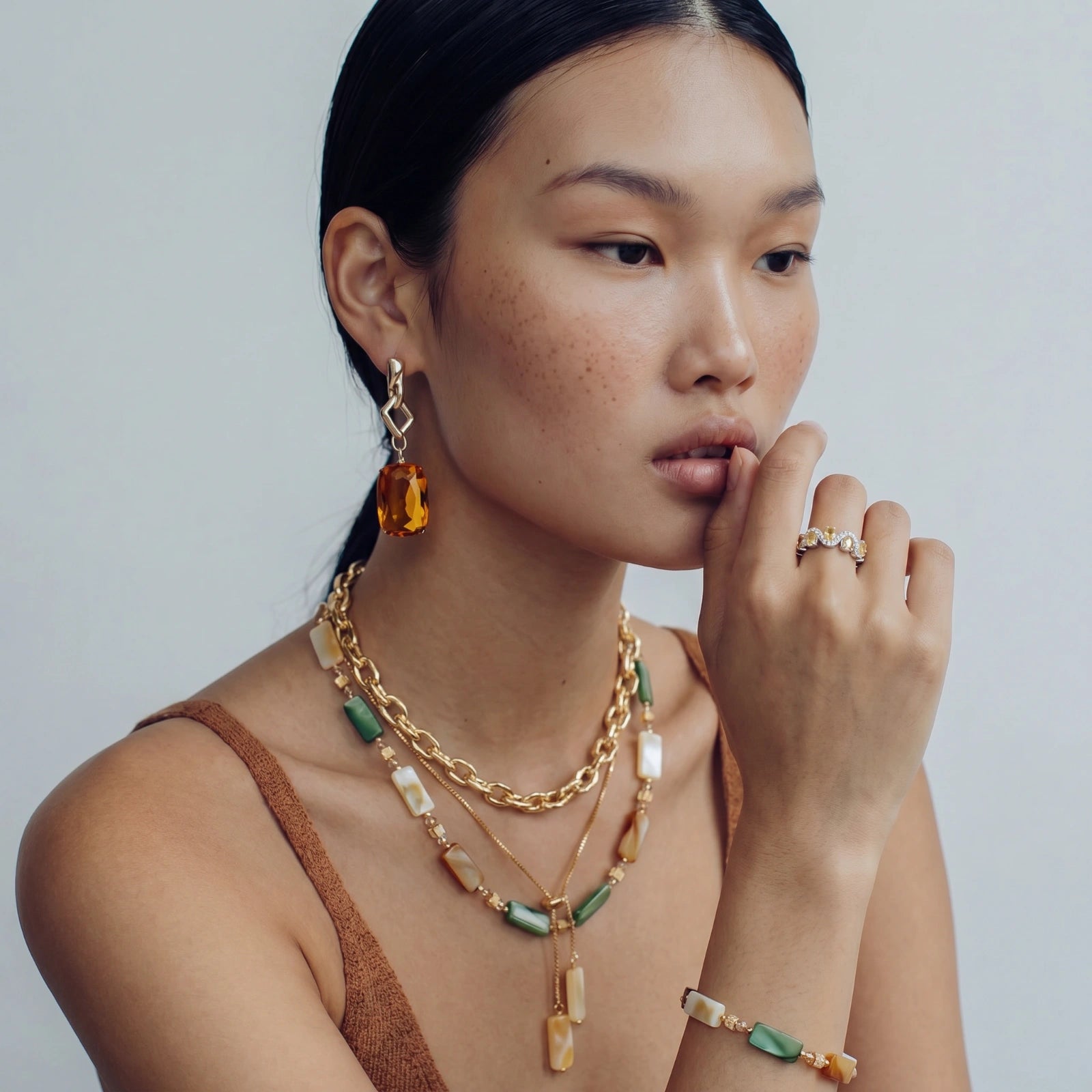 Model showcasing the Sunset Shell Bracelet alongside elegant gold-toned jewellery, featuring hues of amber, green, and cream.