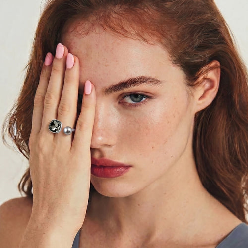 Model showcasing the Dual Element Ring featuring a smoky crystal and grey pearl against her hand.