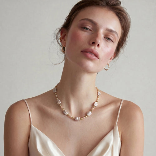Soft pink baroque and round pearls elegantly arranged on a refined gold beaded chain, exuding timeless elegance.