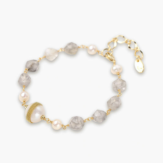 Delicate bracelet featuring round pearls and grey gemstones on a slim gold chain, with an adjustable extender and gold-banded pearl.