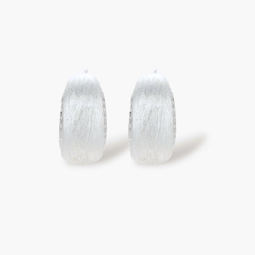 Close-up of small silver-plated hoop earrings with brushed texture and a row of sparkling zircon crystals on white background