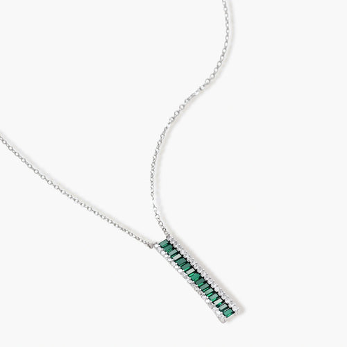 White gold plated jewelry set with emerald green rectangular stones and clear crystals in geometric rows on white background.