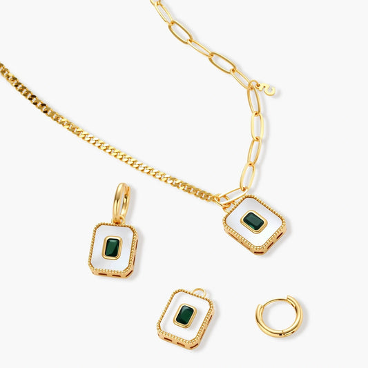 Gold-plated jewelry set with white enamel square pendants and emerald CZ stones on cream background.