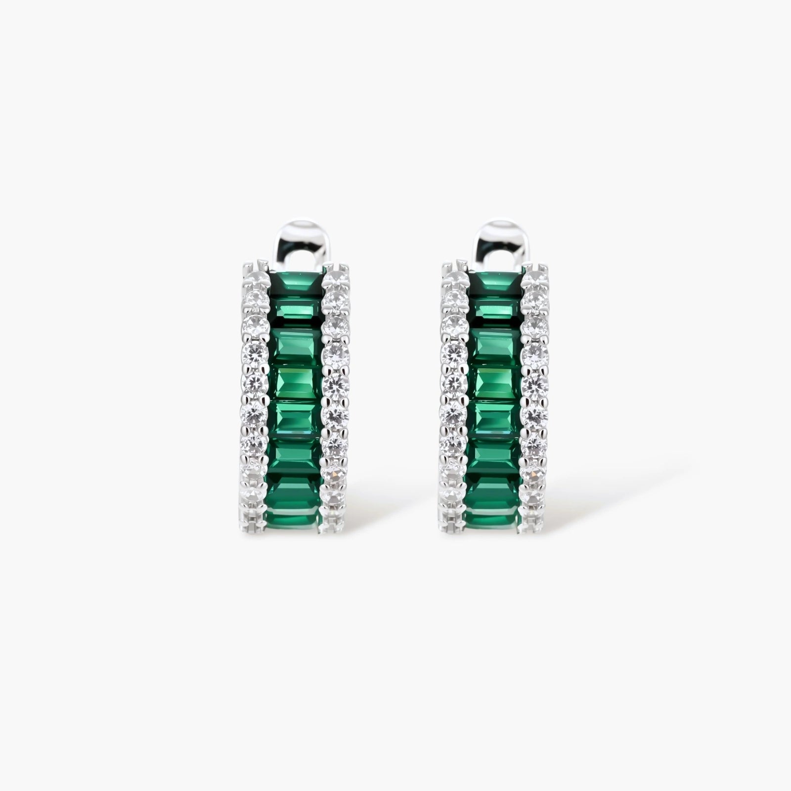 White gold plated jewelry set with emerald green rectangular stones and clear crystals in geometric rows on white background.