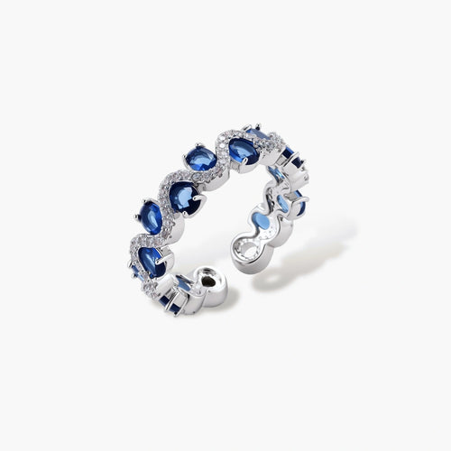 Adjustable ring with blue cubic zirconia stones in flowing wave pattern, copper with platinum plating on white background.