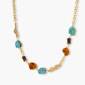 Statement necklace with gold chain, turquoise stones, amber beads, and wooden elements on cream background.