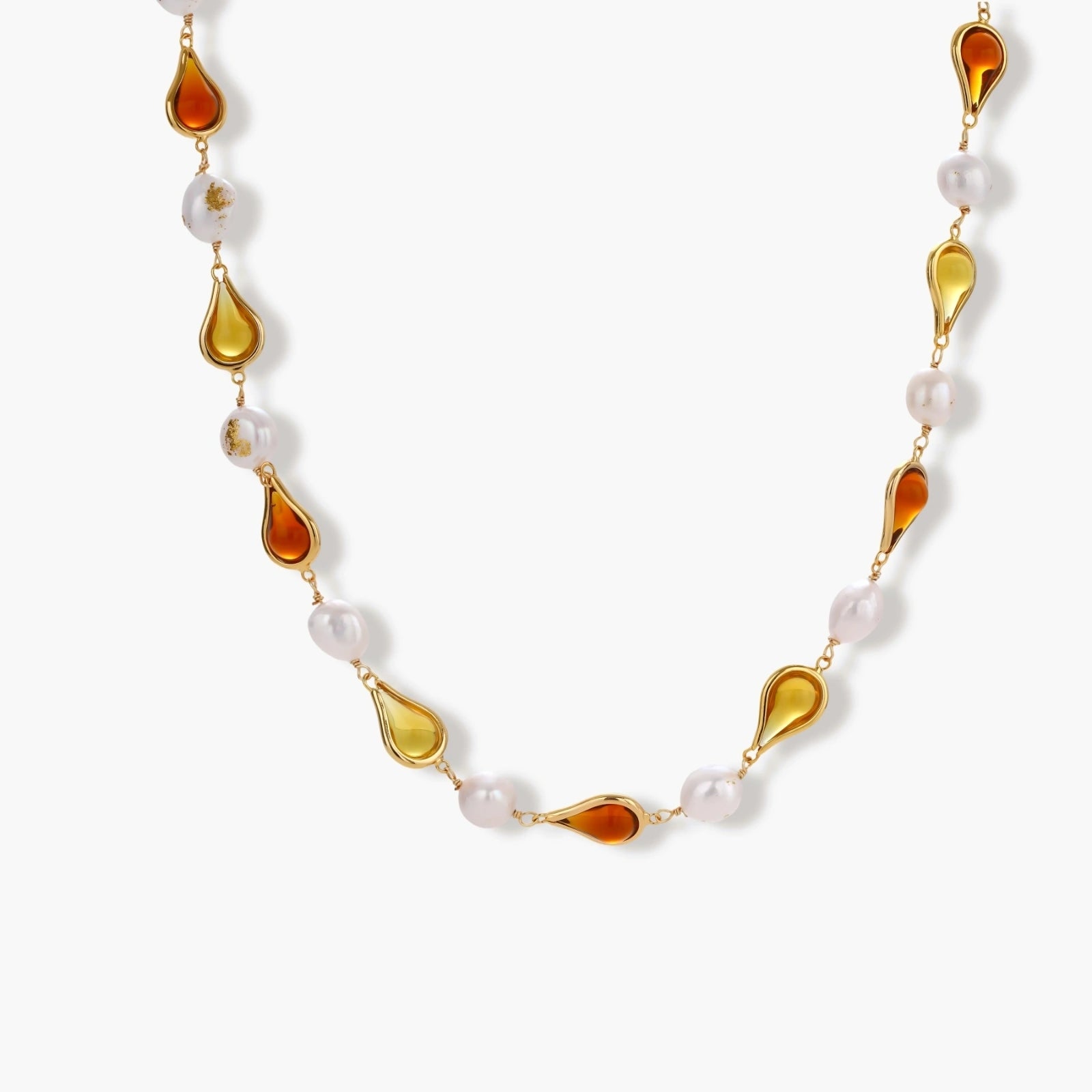Gold-plated copper necklace with amber teardrop settings and white baroque freshwater pearls on cream background.