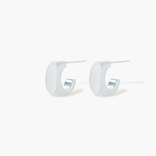 Pair of small silver-plated huggie hoop earrings with clean minimal design on neutral background.
