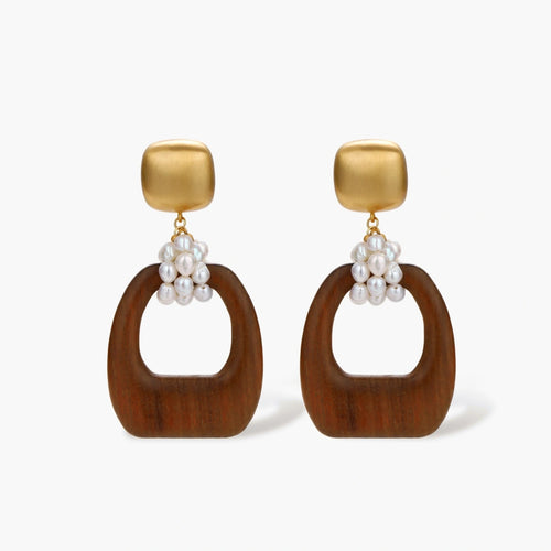 Gold-plated stud earrings with pearl clusters and organic brown wooden hoops on cream background