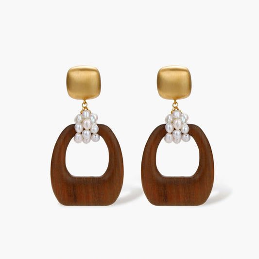 Gold-plated stud earrings with pearl clusters and organic brown wooden hoops on cream background
