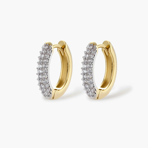 Gold-plated curved necklace, hoop earrings, and adjustable ring with pavé cubic zirconia stones on cream background.