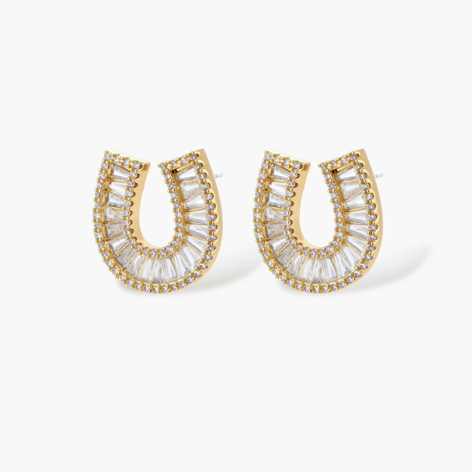 Gold-plated horseshoe necklace and earring set with baguette and round crystals arranged in geometric pattern on white background.