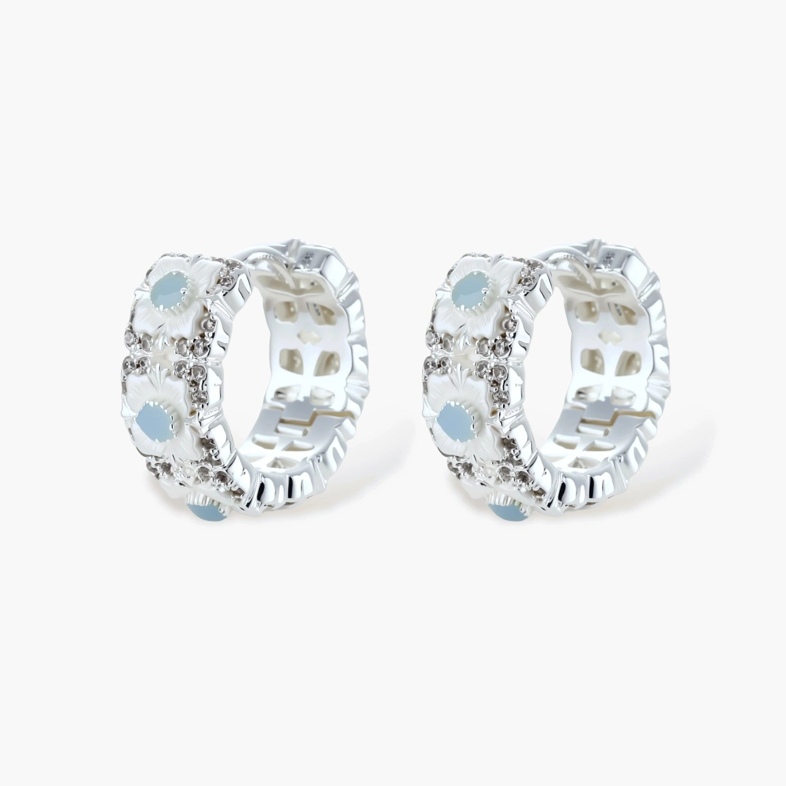 Silver-plated hoop earrings featuring delicate daisy flowers with powder blue centers and crystal accents on white background.