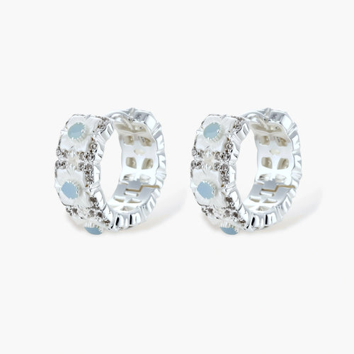 Silver-plated hoop earrings featuring delicate daisy flowers with powder blue centers and crystal accents on white background.