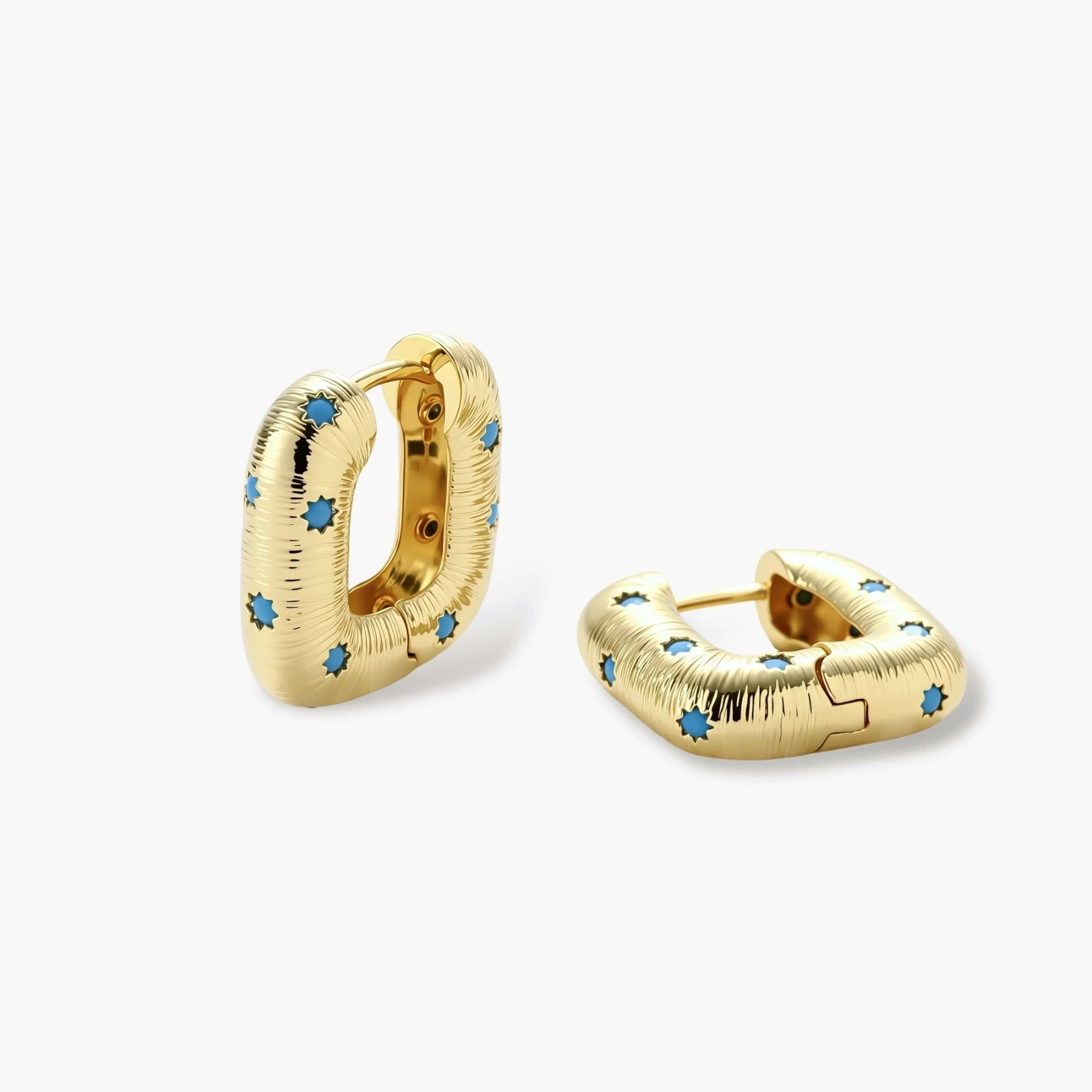 Gold-plated huggie hoop earrings with blue star inlays and textured surface, shown against white background.