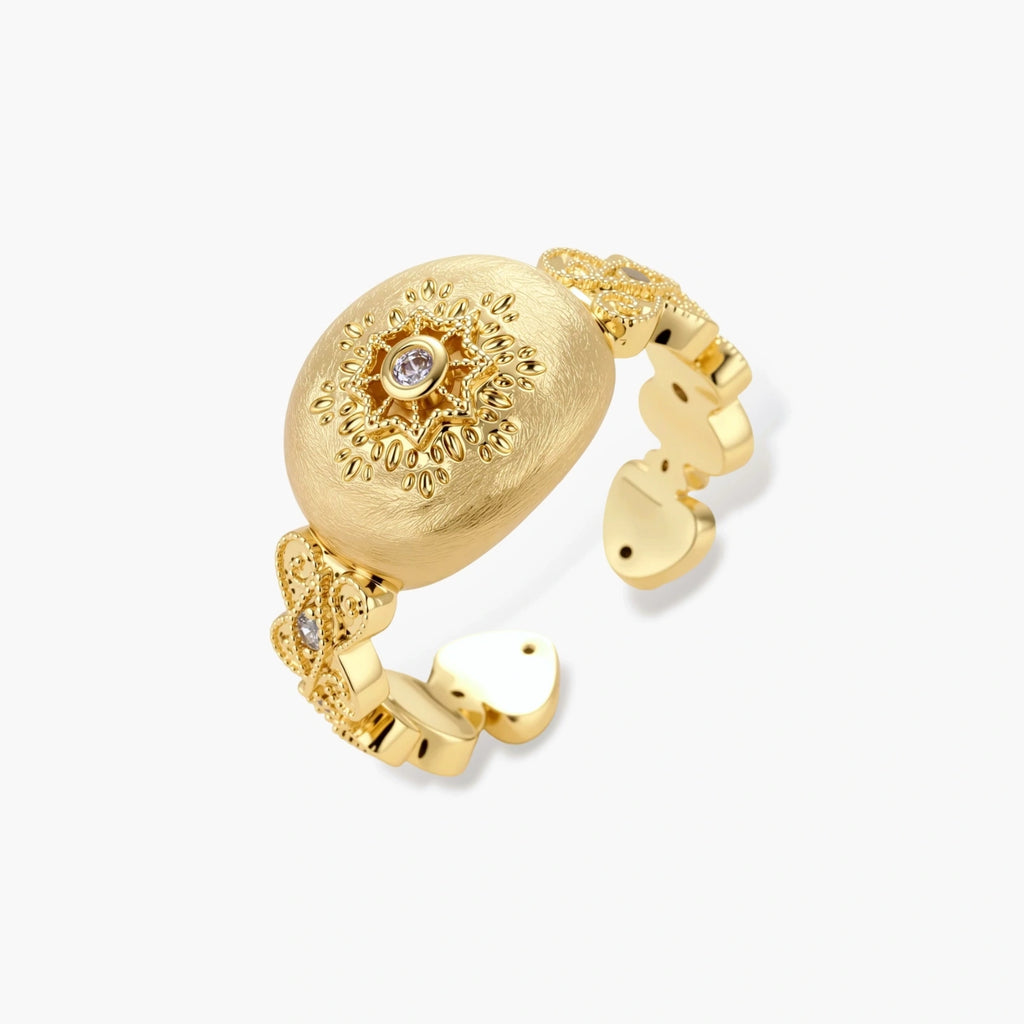 Ornate gold-plated ring with detailed engravings and central zirconia stone on adjustable band