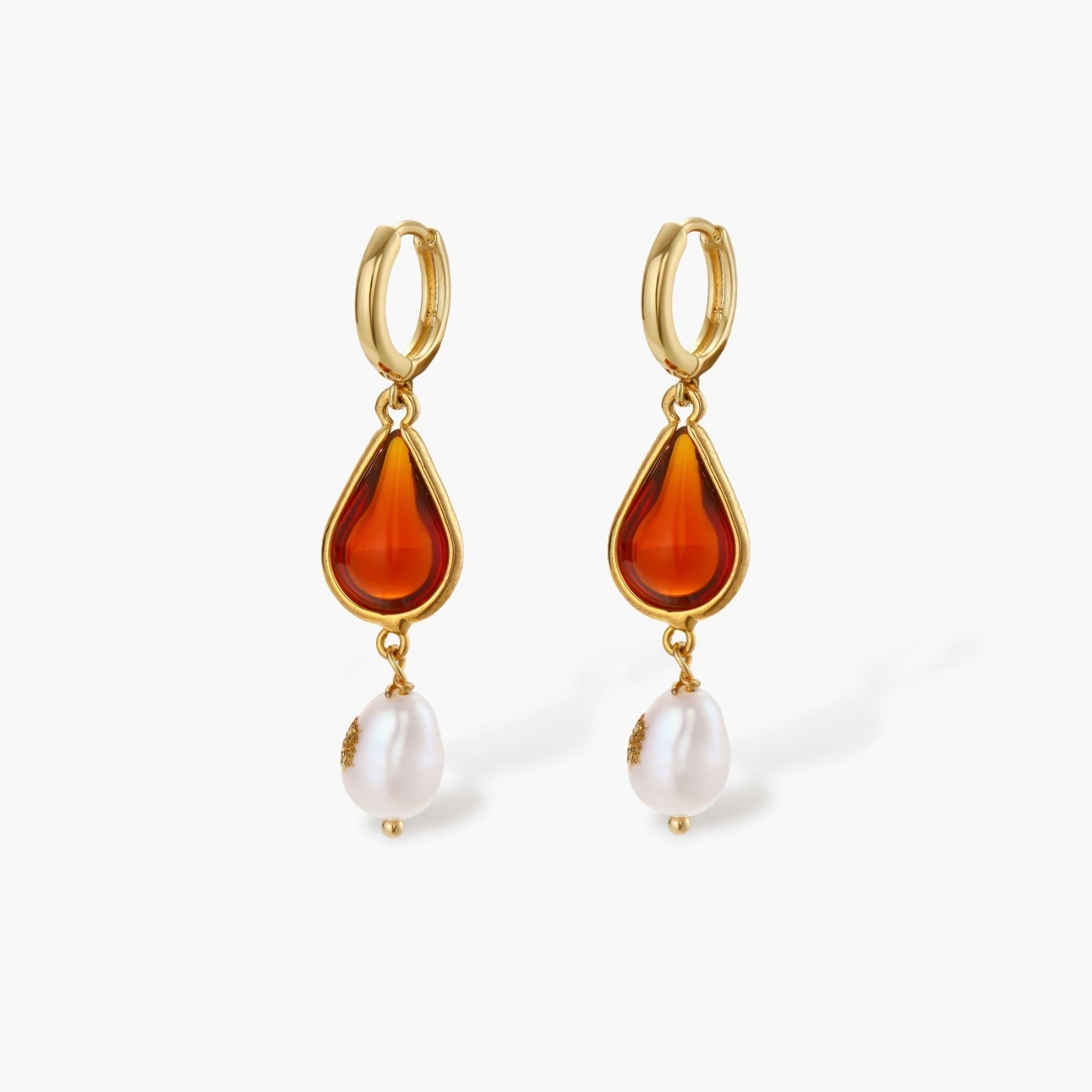 Gold-plated drop earrings featuring amber teardrops and white baroque pearls on light background.