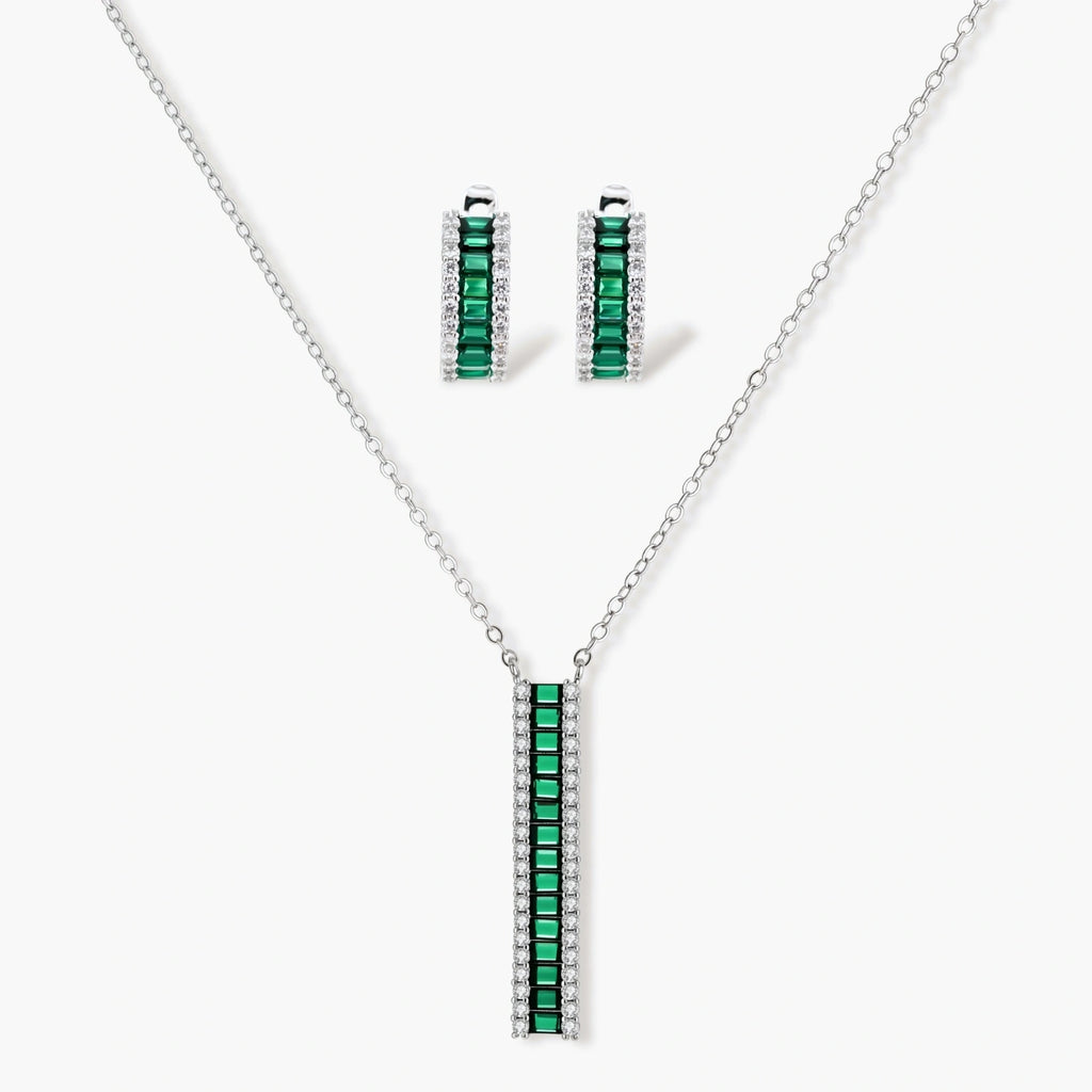 White gold plated jewelry set with emerald green rectangular stones and clear crystals in geometric rows on white background.