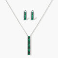 White gold plated jewelry set with emerald green rectangular stones and clear crystals in geometric rows on white background.