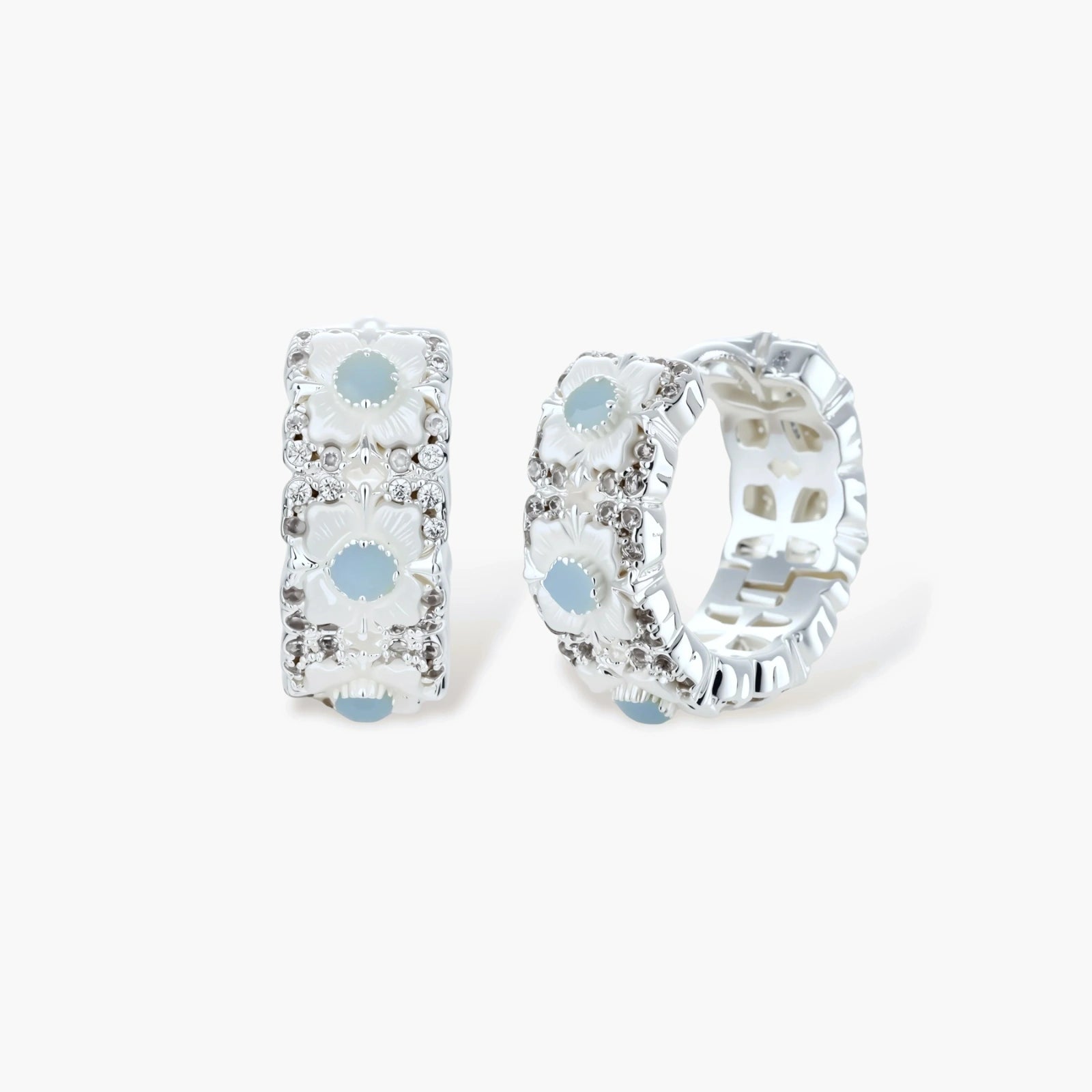Silver-plated hoop earrings featuring delicate daisy flowers with powder blue centers and crystal accents on white background.