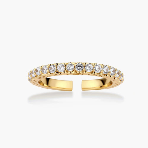 Close-up of adjustable gold-plated ring with continuous row of round zirconia stones on neutral background.
